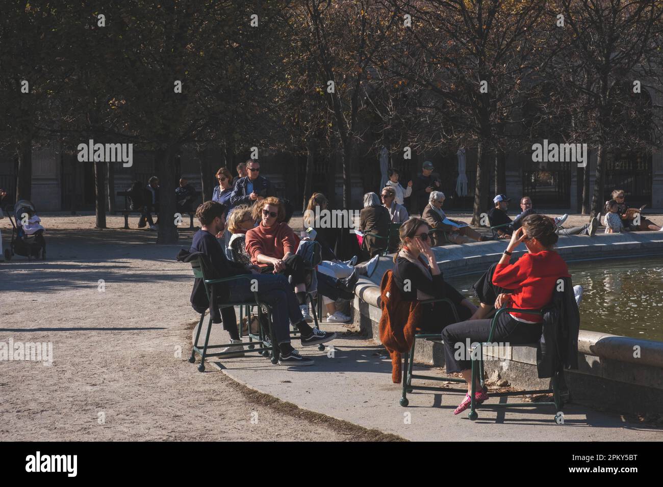 Les gens élégants se détendent sur des chaises publiques près d'un étang dans un jardin parisien Banque D'Images