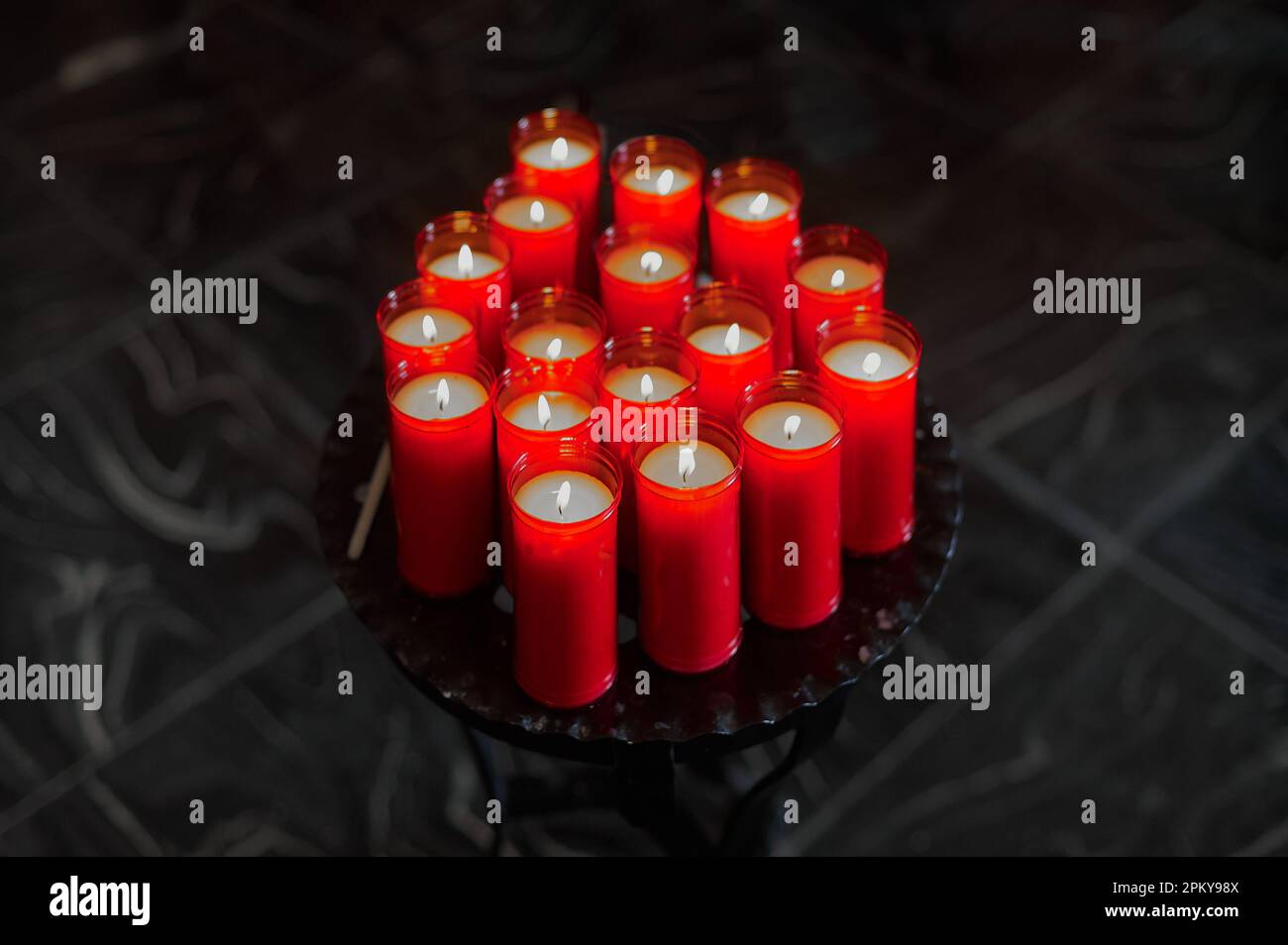 Plateau rond avec plusieurs bougies allumées encapsulées dans du plastique orange Banque D'Images