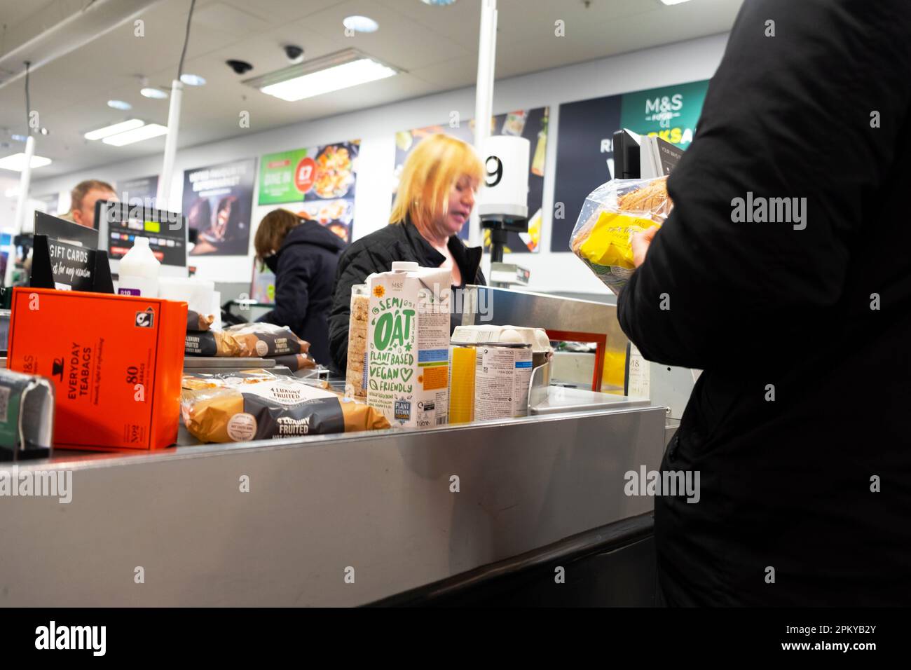 Femme travailleuse salariée âgée au service du client à Marks and Spencer M&S comptoir de caisse Royaume-Uni avril 2023 Grande-Bretagne KATHY DEWITT Banque D'Images