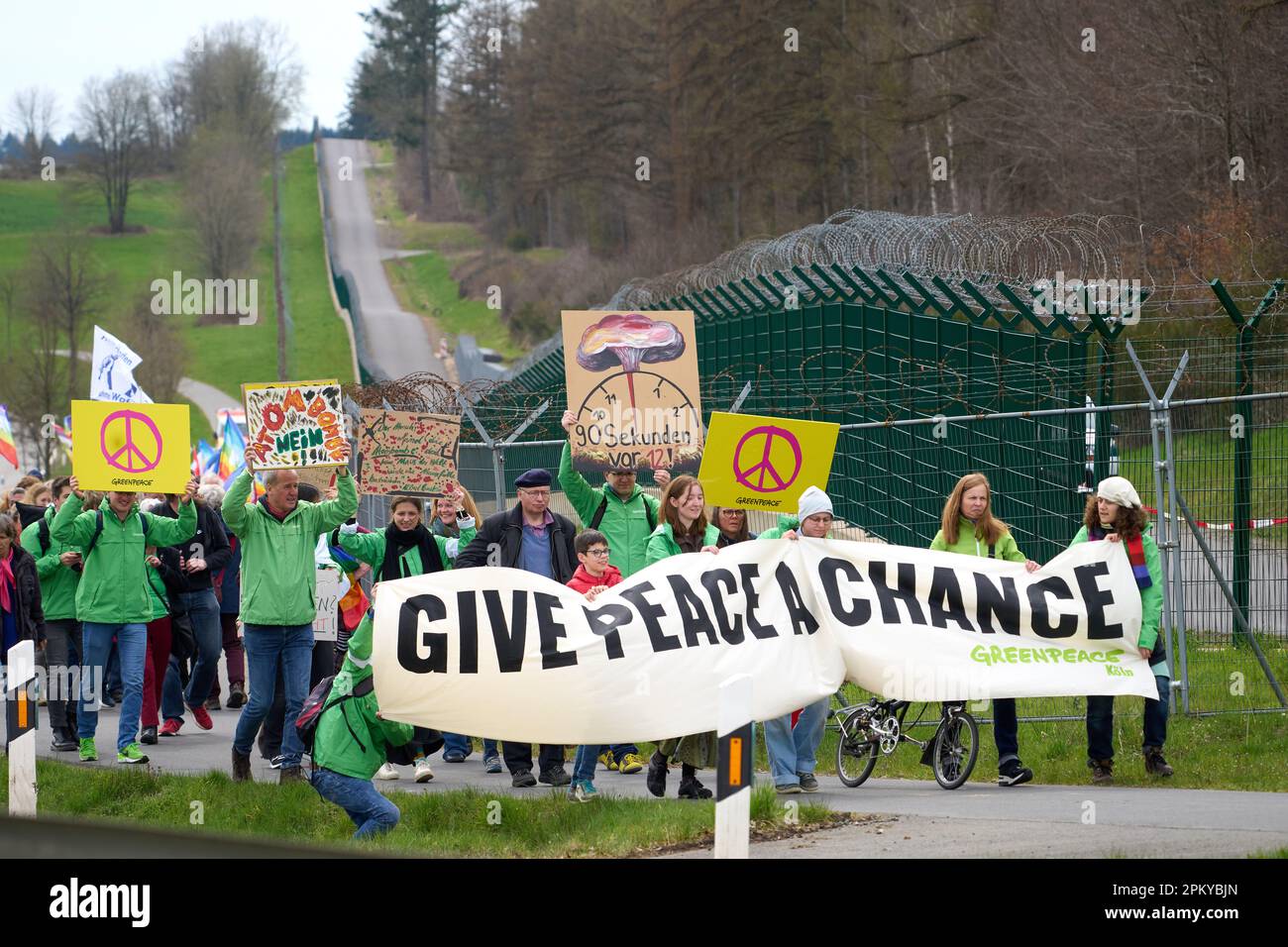 10 avril 2023, Rhénanie-Palatinat, Büchel : les participants à la marche de Pâques marchent à côté de la clôture de la base aérienne de Bundeswehr à Büchel. En 2023, de nombreuses marches de Pâques ont également eu lieu à travers l'Allemagne sous l'impression de la guerre de la Russie contre l'Ukraine. Photo: Thomas Frey/dpa Banque D'Images