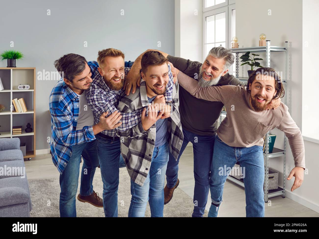 Groupe d'hommes joyeux et excités félicitant leur ami pour un événement heureux dans sa vie Banque D'Images