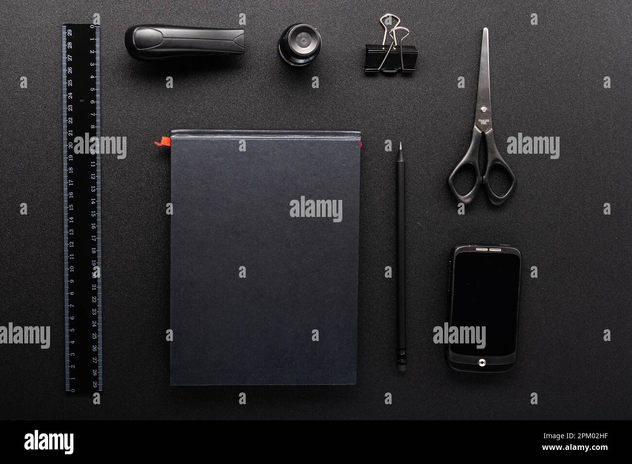 Fournitures de bureau soigneusement disposées sur la table. Objets noirs sur une table noire. Sur le bureau. Vue de dessus. Banque D'Images