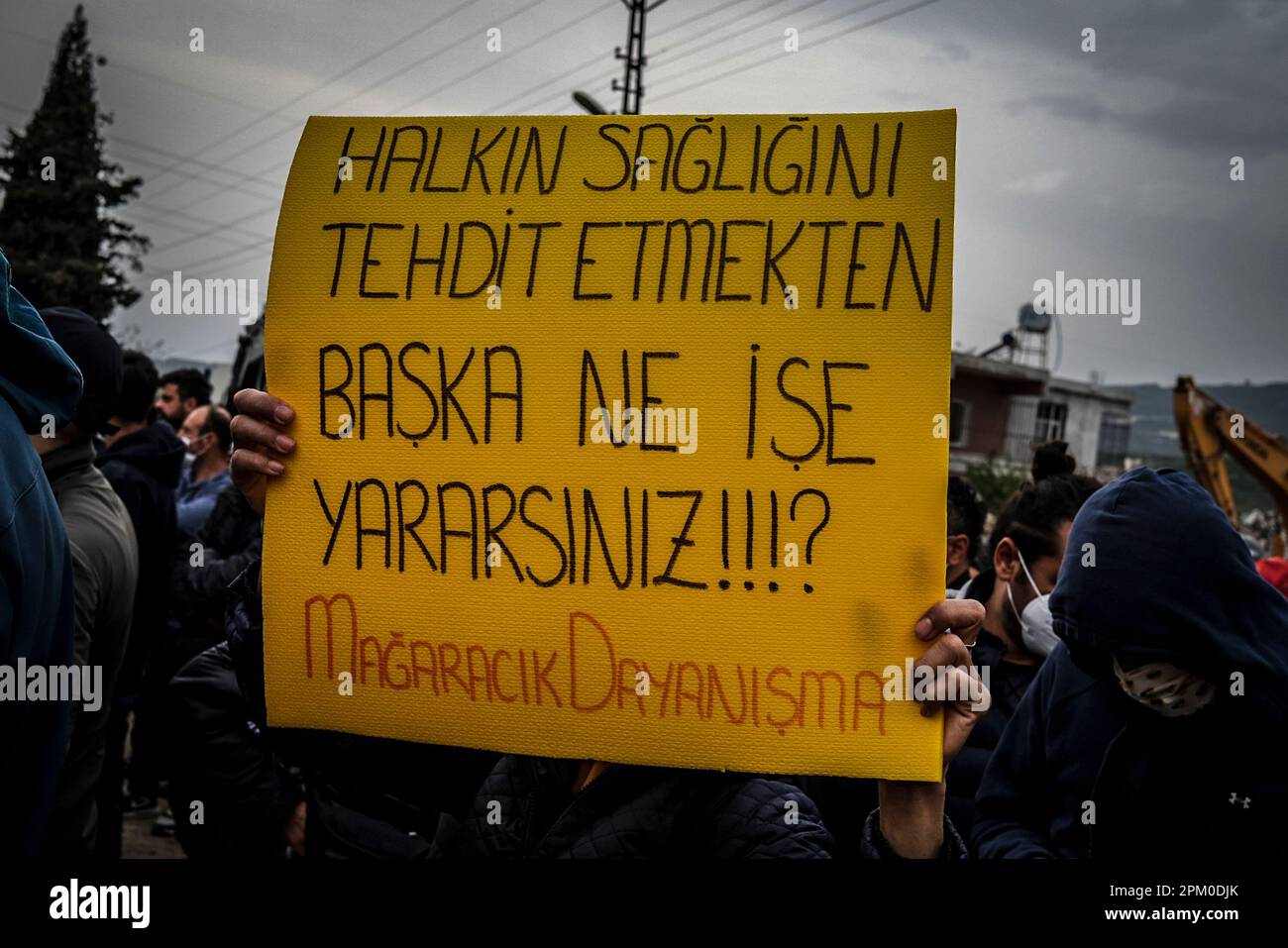 Un manifestant tient un écriteau qui indique « que faites-vous autre que de menacer la santé publique » pendant la démonstration. Samanda de Hatay ? district est un point où les décombres des bâtiments détruits dans le tremblement de terre a été versé. Les professionnels de la santé et les universitaires pensent que le fait de renverser les décombres dans la nature provoquera un cancer pour les habitants de la région et que la poussière émise par les décombres contient de l'amiante et que le mélange avec le sol et l'eau causera de nombreuses maladies, donc un grand nombre de personnes sont venues en protestation de ce . Banque D'Images