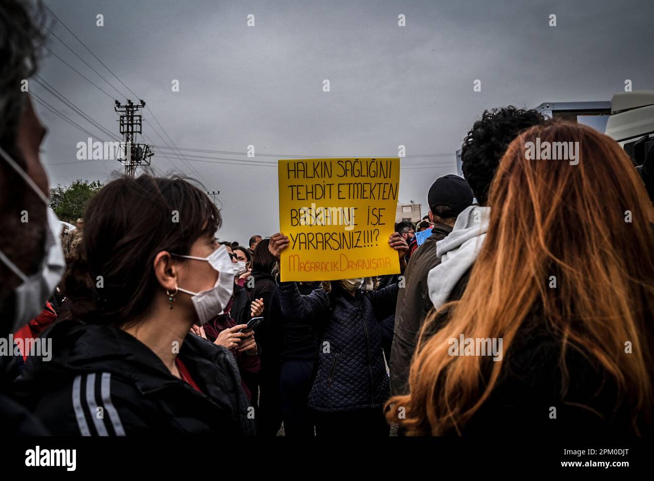 Un manifestant tient un écriteau qui indique « que faites-vous autre que de menacer la santé publique » pendant la démonstration. Samanda de Hatay ? district est un point où les décombres des bâtiments détruits dans le tremblement de terre a été versé. Les professionnels de la santé et les universitaires pensent que le fait de renverser les décombres dans la nature provoquera un cancer pour les habitants de la région et que la poussière émise par les décombres contient de l'amiante et que le mélange avec le sol et l'eau causera de nombreuses maladies, donc un grand nombre de personnes sont venues en protestation de ce . Banque D'Images