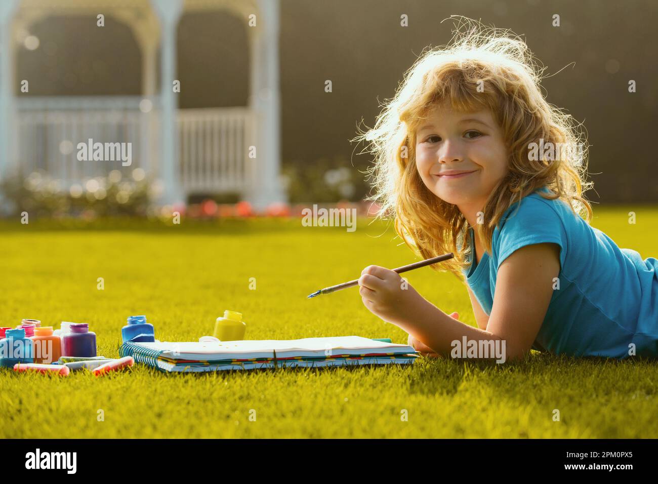 Un enfant s'amuse dans un parc reposant sur de l'herbe, sur fond de nature. Enfant heureux jouant à l'extérieur. Dessin du thème d'été. Imagination pour enfants. Banque D'Images