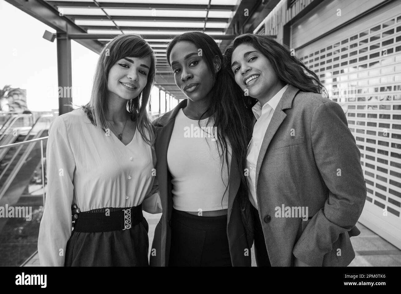 Trois femmes d'affaires souriant ensemble, collègues au travail, photo en noir et blanc. Banque D'Images
