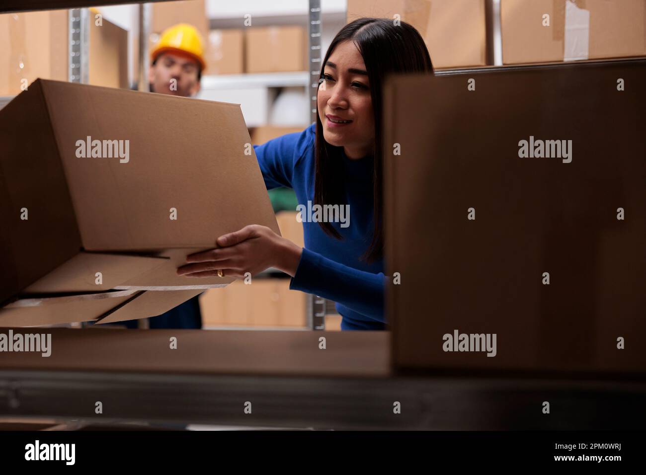 Le responsable de la logistique effectue le contrôle de la qualité des colis de marchandises tout en recherchant des boîtes en carton sur les tablettes. Emballage de stockage des employés de l'eCommerce Retail pour emballer la commande du client en vue de son expédition Banque D'Images