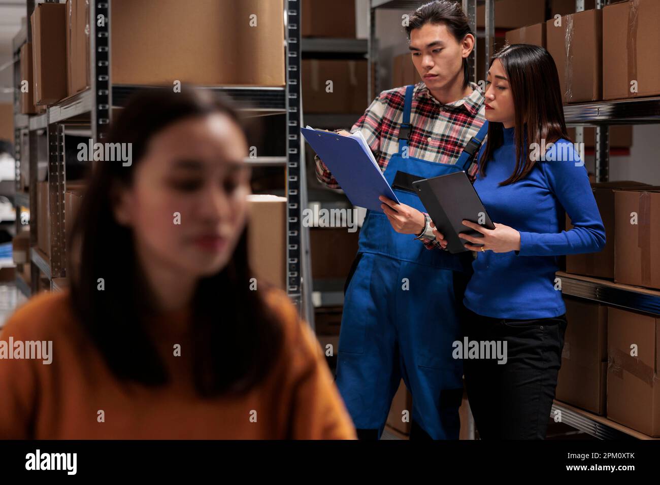 Les employés des magasins de vente au détail ramassant la commande du client à l'aide de la liste de contrôle sur le presse-papiers Les employés des entrepôts industriels se trouvant près du plateau des colis, analysant la liste des marchandises et effectuant l'inventaire Banque D'Images