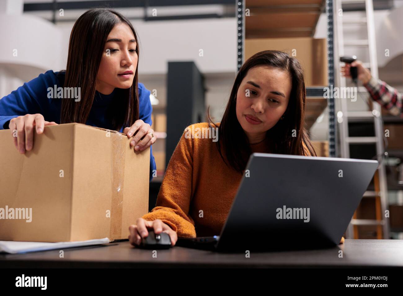 Les travailleurs asiatiques des magasins effectuent le contrôle de la qualité des colis et gèrent la livraison. ECommerce Retail business warehouse jeunes femmes collègues de suivi de l'expédition de commande en ligne sur ordinateur portable Banque D'Images