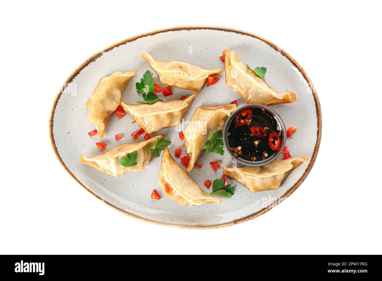 Assiette avec de savoureux jiaozi chinois, persil et sauce sur fond blanc Banque D'Images