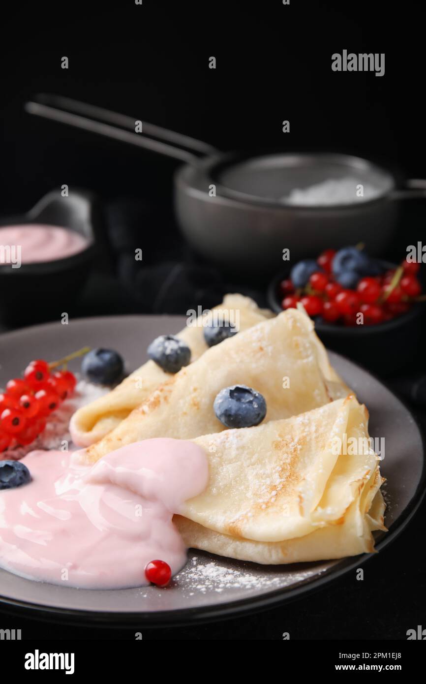 Crêpes délicieuses avec yaourt naturel, bleuets et raisins de Corinthe rouges sur table, en gros plan Banque D'Images