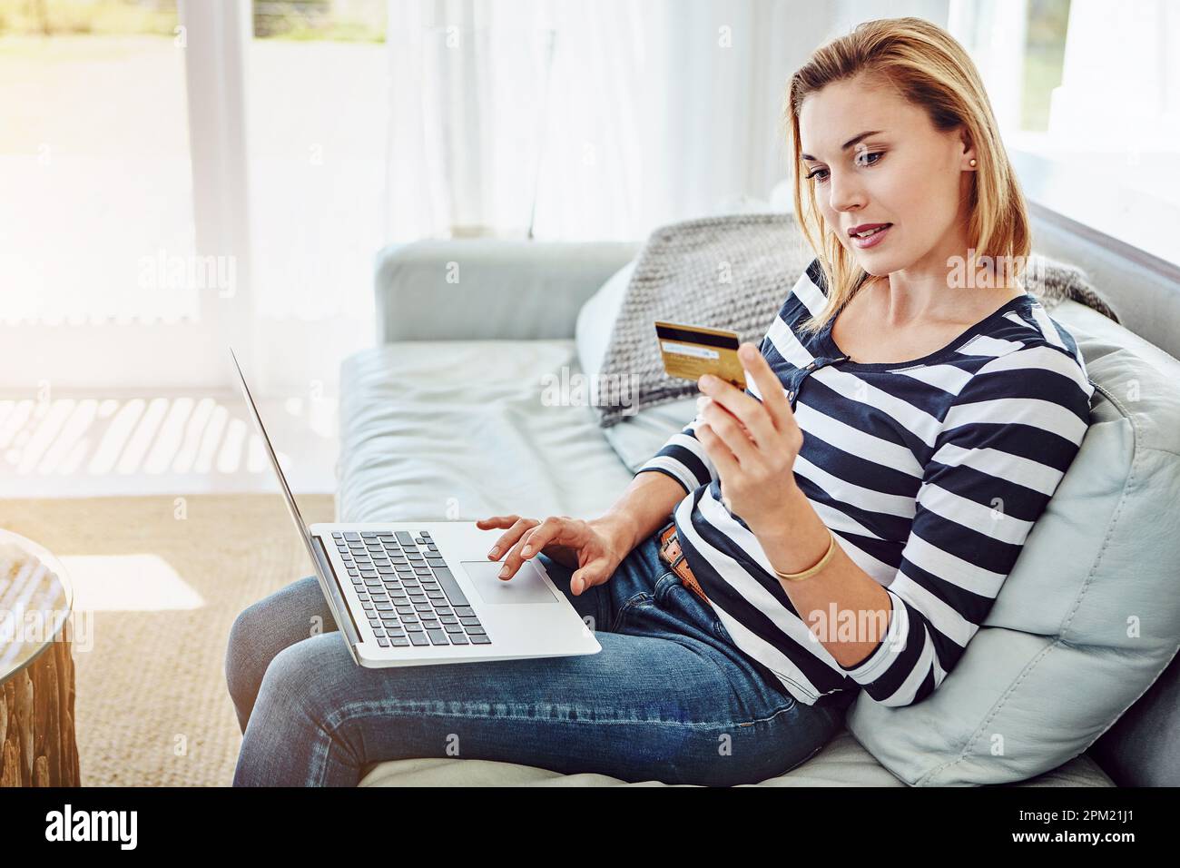 Achats en ligne. Prise de vue en grand angle d'une jeune femme attrayante magasiner en ligne depuis le confort de la maison. Banque D'Images