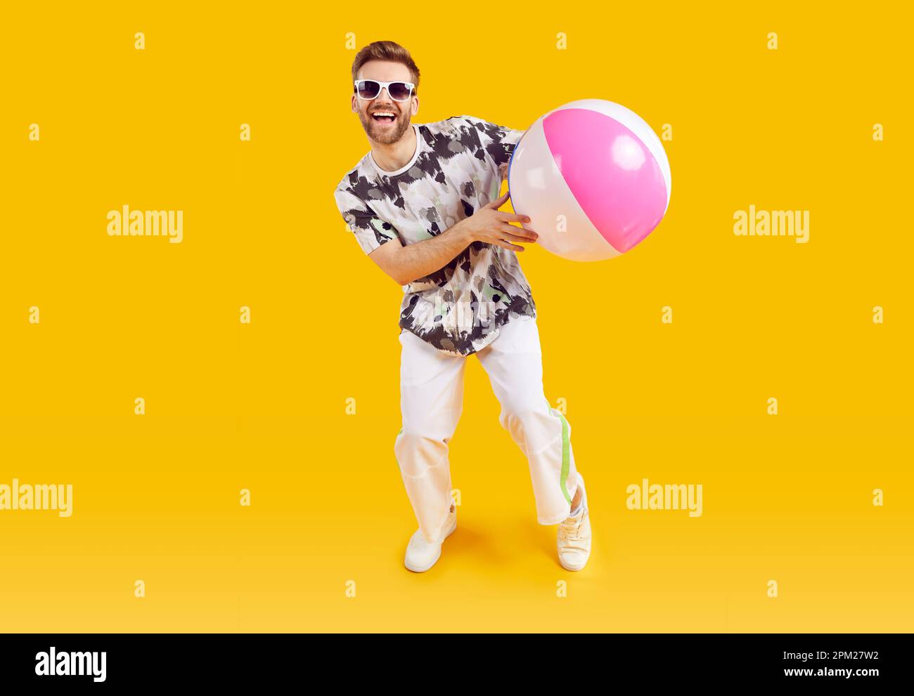 Sourire joyeux gars dans des lunettes de soleil tenant ballon gonflable de mer Banque D'Images