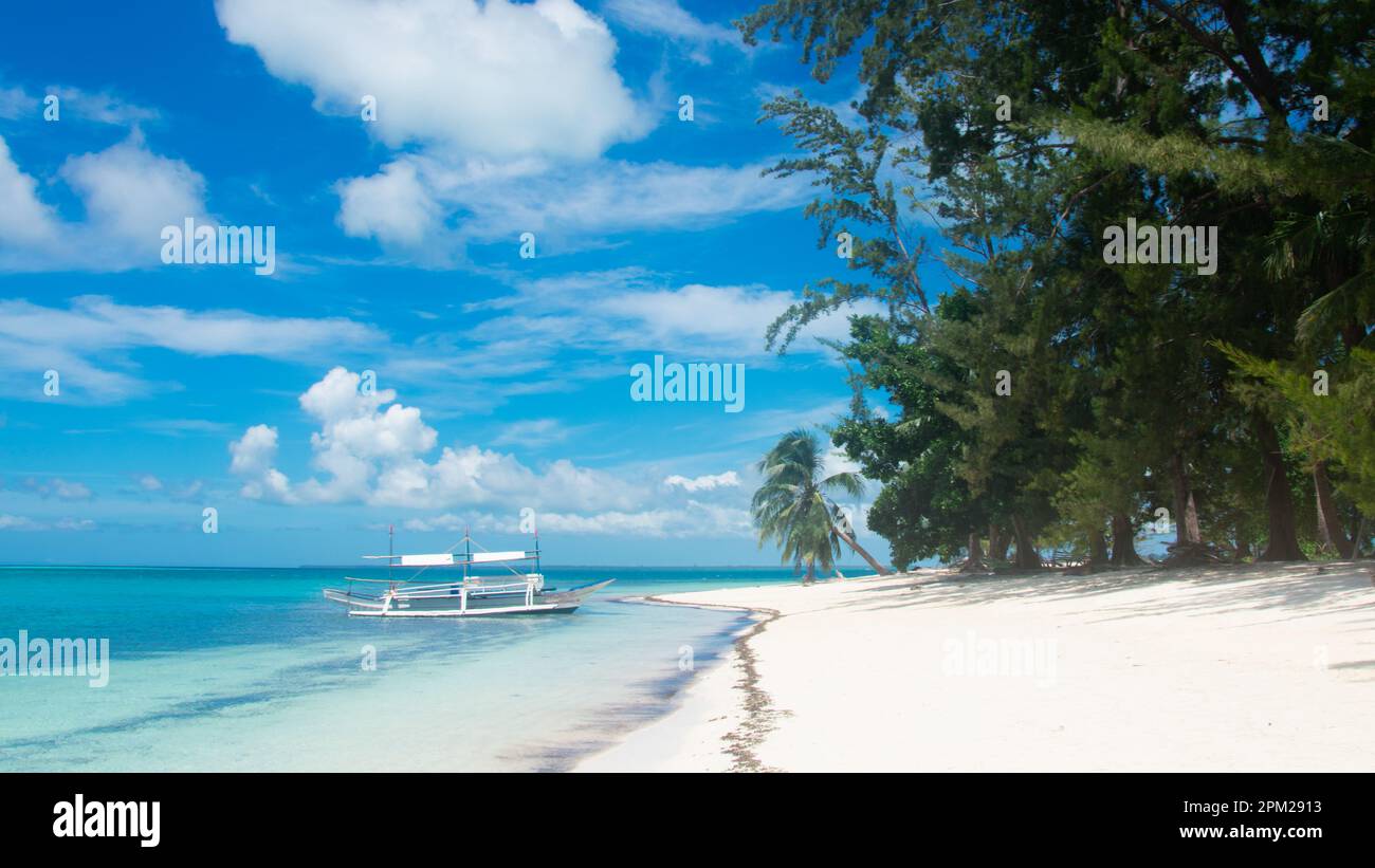Bateau traditionnel en bois sur des eaux turquoises, plage de sable blanc et palmiers dans les îles Balabac, Philippines - une escapade tropicale sereine Banque D'Images