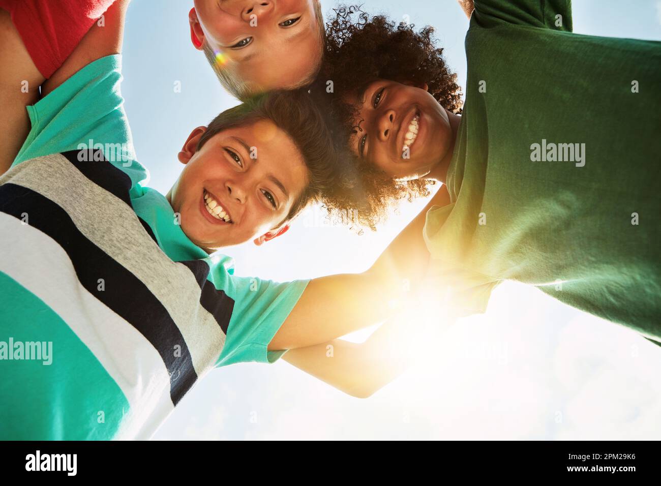 L'amitié fait le tour du monde. Portrait d'un groupe d'enfants divers et heureux qui se sont rassemblés lors d'une journée de grand soleil à l'extérieur. Banque D'Images