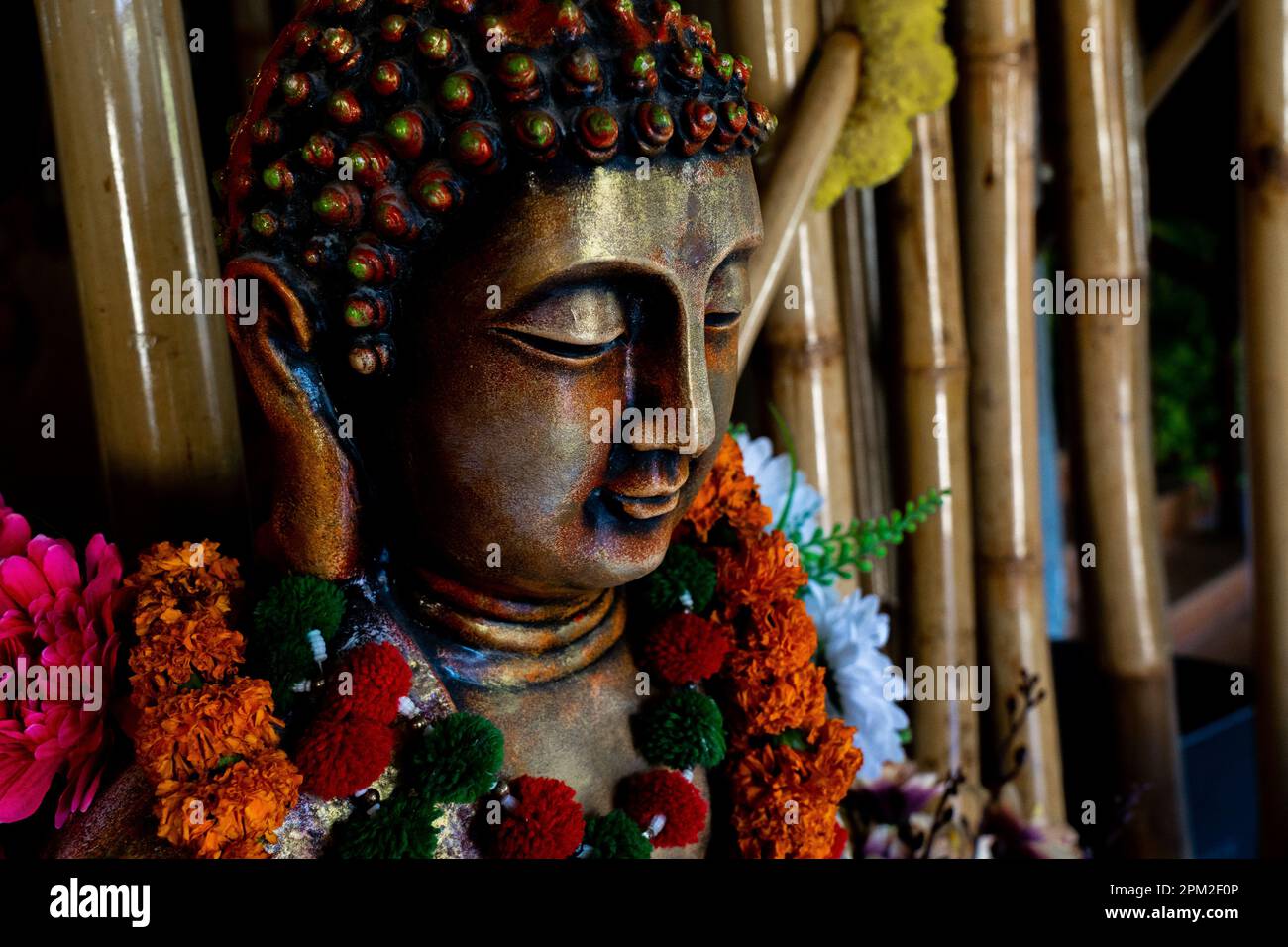 Gros plan de la statue de bouddha de bronze assis dans la méditation avec des décorations de fleur pour la cérémonie de festival. Photo de haute qualité Banque D'Images