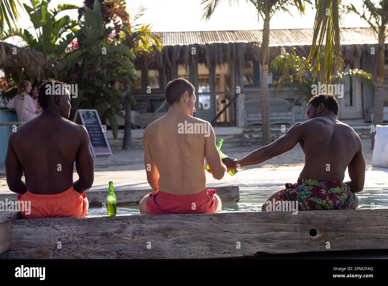 Joyeux amis de sexe masculin divers en faisant la fête près de la piscine, en buvant de la bière Banque D'Images