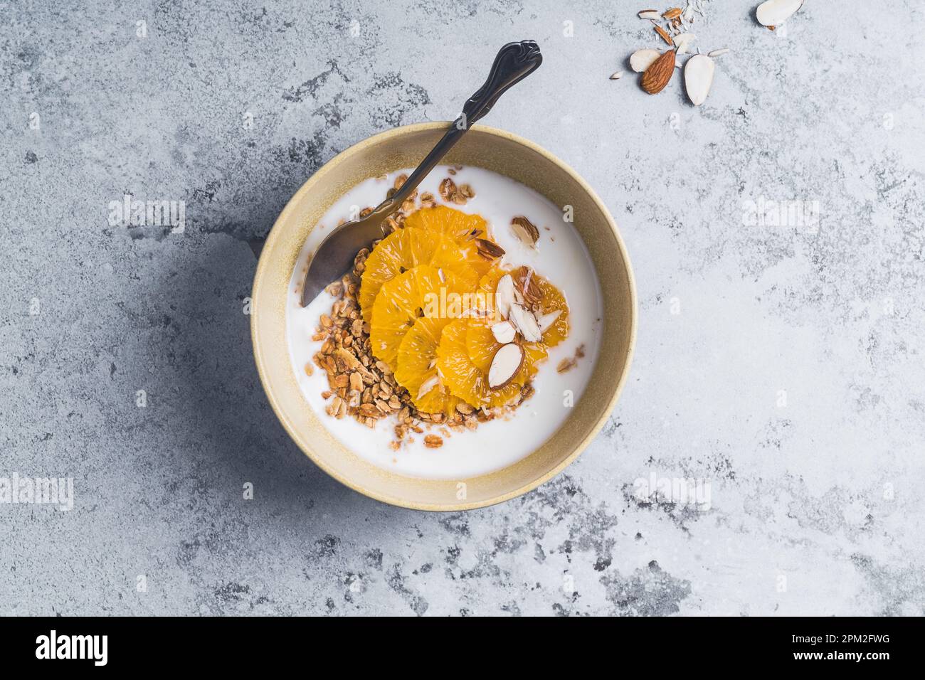 Bols de céréales au yaourt avec fruits orange sur tableau gris, vue du dessus. Repas végétarien sain pour le petit déjeuner Banque D'Images