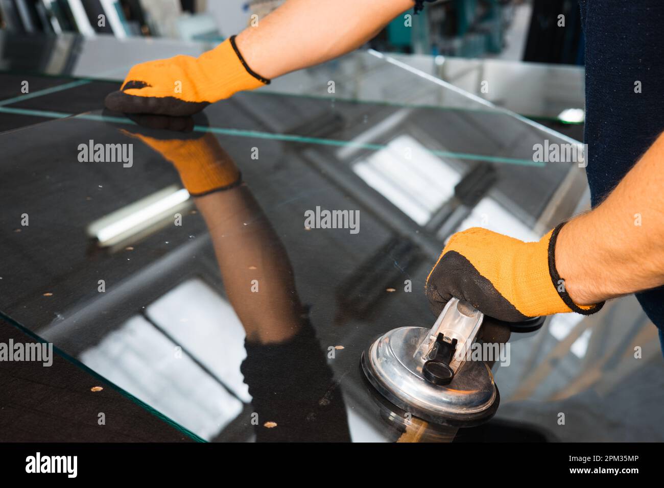 Un vitrier dans une usine de verre enlève le verre lourd à l'aide de ventouses, outils industriels spécialisés Banque D'Images