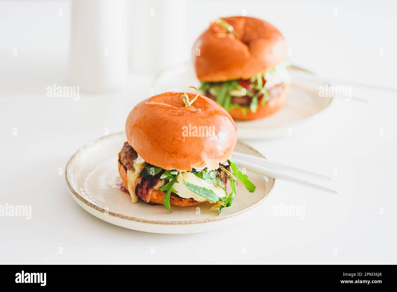 Deux délicieux hamburgers faits maison avec du bœuf, du fromage et des légumes sur une table en bois blanc Banque D'Images
