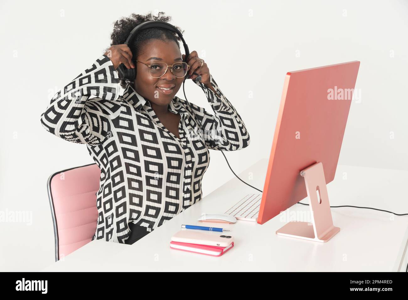 Angleterre, Royaume-Uni. 2023. Femme téléphoniste portant un casque assis à l'ordinateur de bureau avec un grand sourire. Banque D'Images