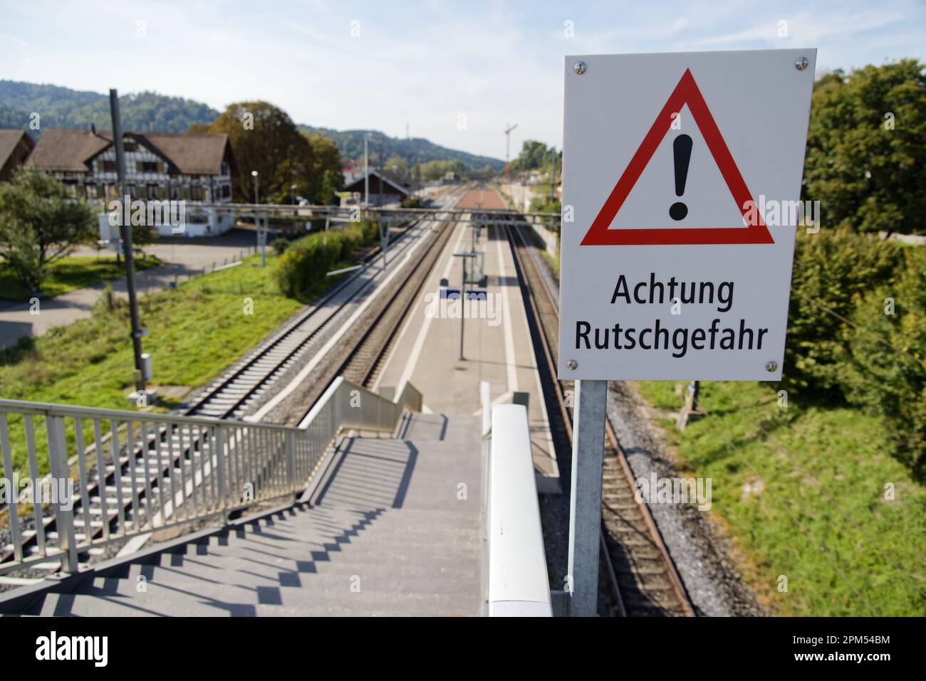 attention danger de glisser signe devant un escalier de gare traduction
