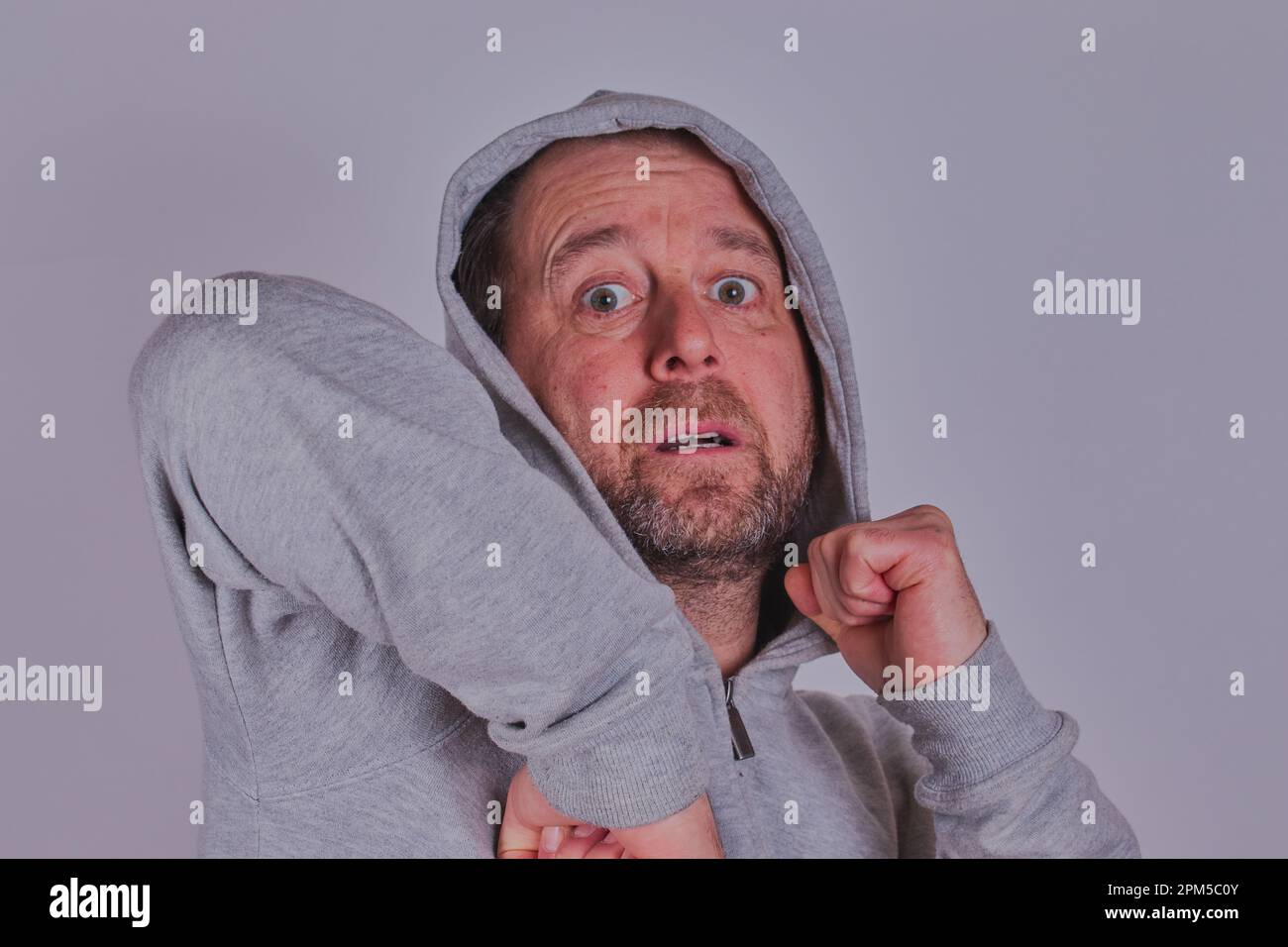 Homme barbu dans un haut de survêtement pratiquant des mouvements d'art martial. Autorisation du modèle disponible. Banque D'Images