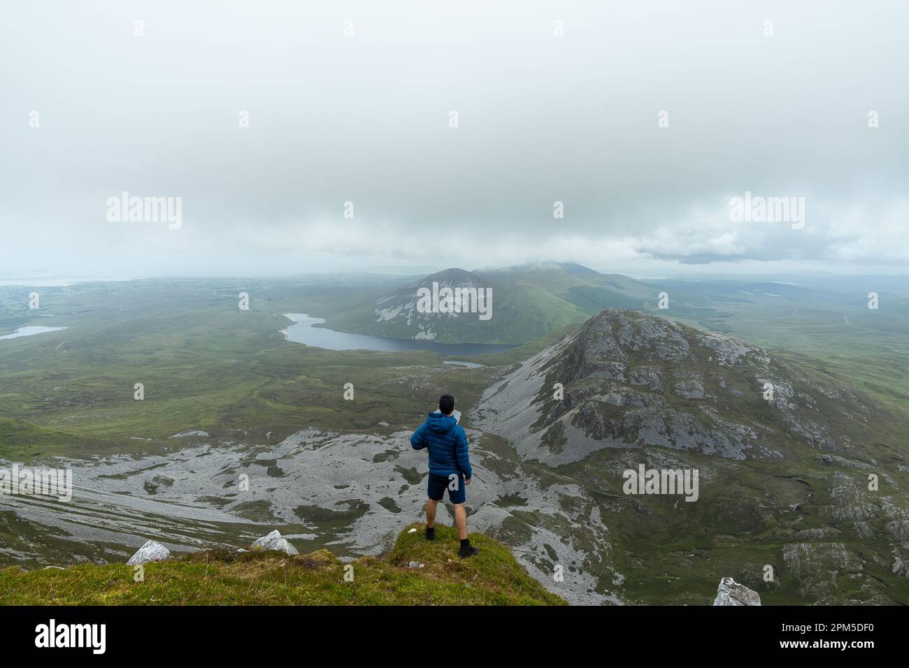 Homme debout au sommet de la montagne et admirant le paysage de la montagne Errigal Banque D'Images