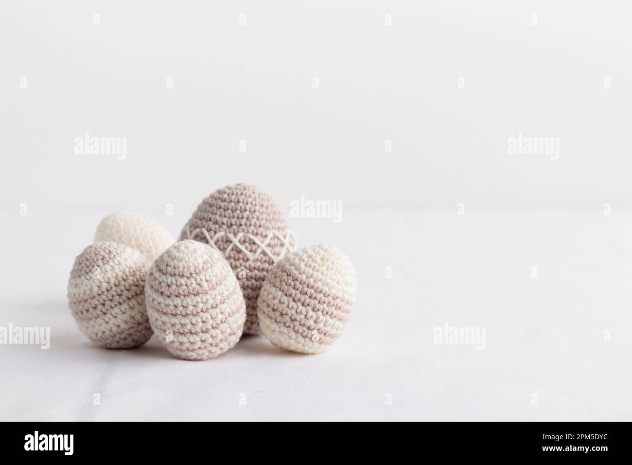Ensemble d'œufs crochetés faits main, couleur pastel sur une table blanche Banque D'Images