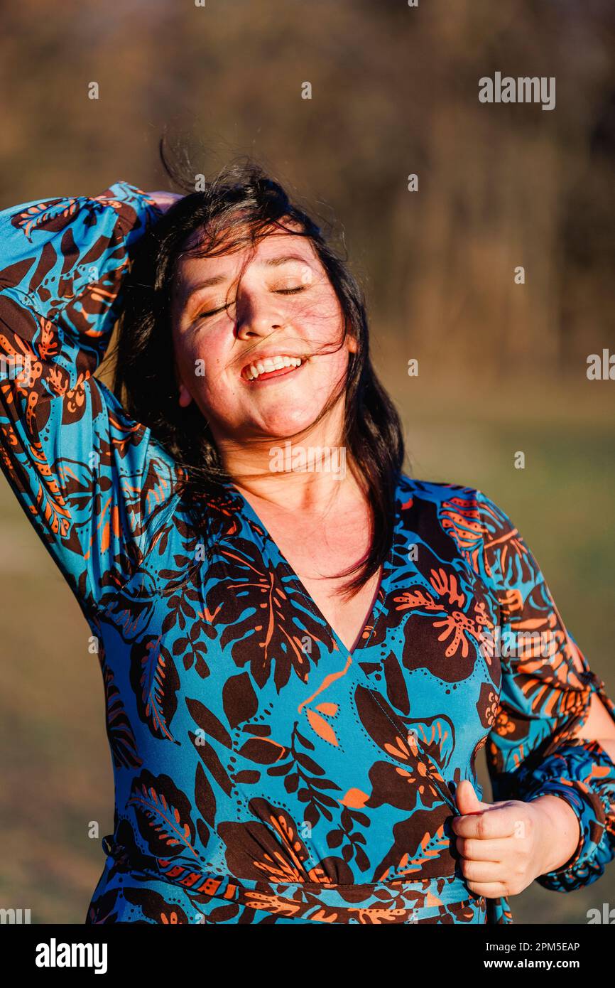 Belle femme souriante avec les yeux fermés à la lumière dorée Banque D'Images