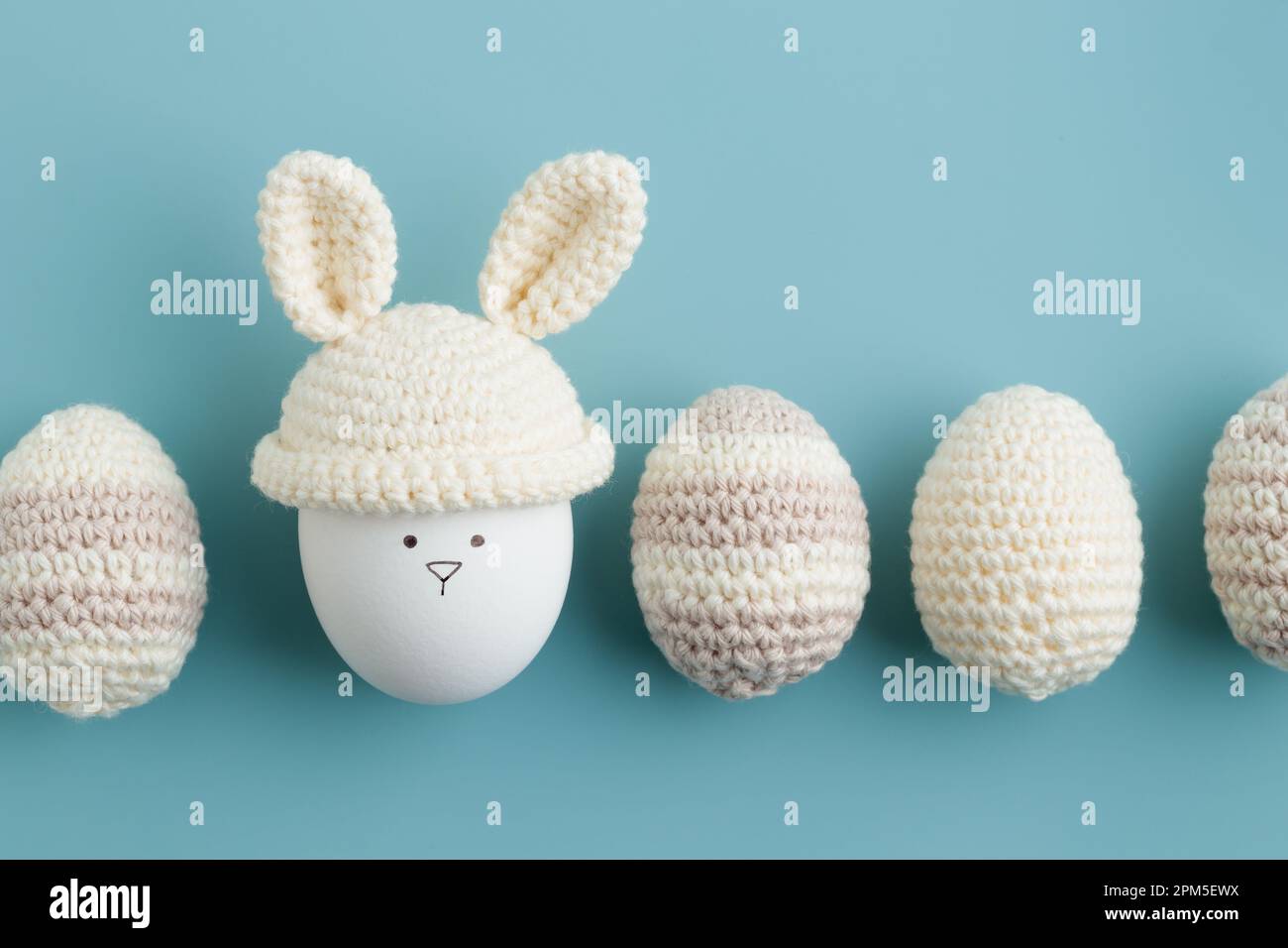 oeufs de pâques dans le chapeau crochet avec des oreilles de lapin sur fond bleu Banque D'Images