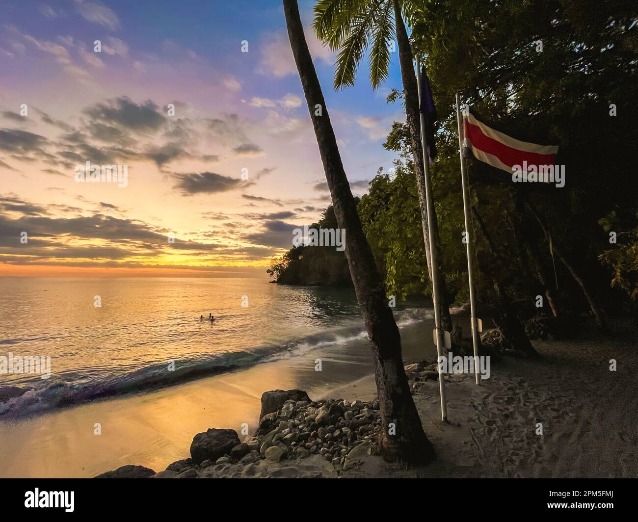 Les personnes nageant au coucher du soleil sur une plage tropicale au Costa Rica. Banque D'Images