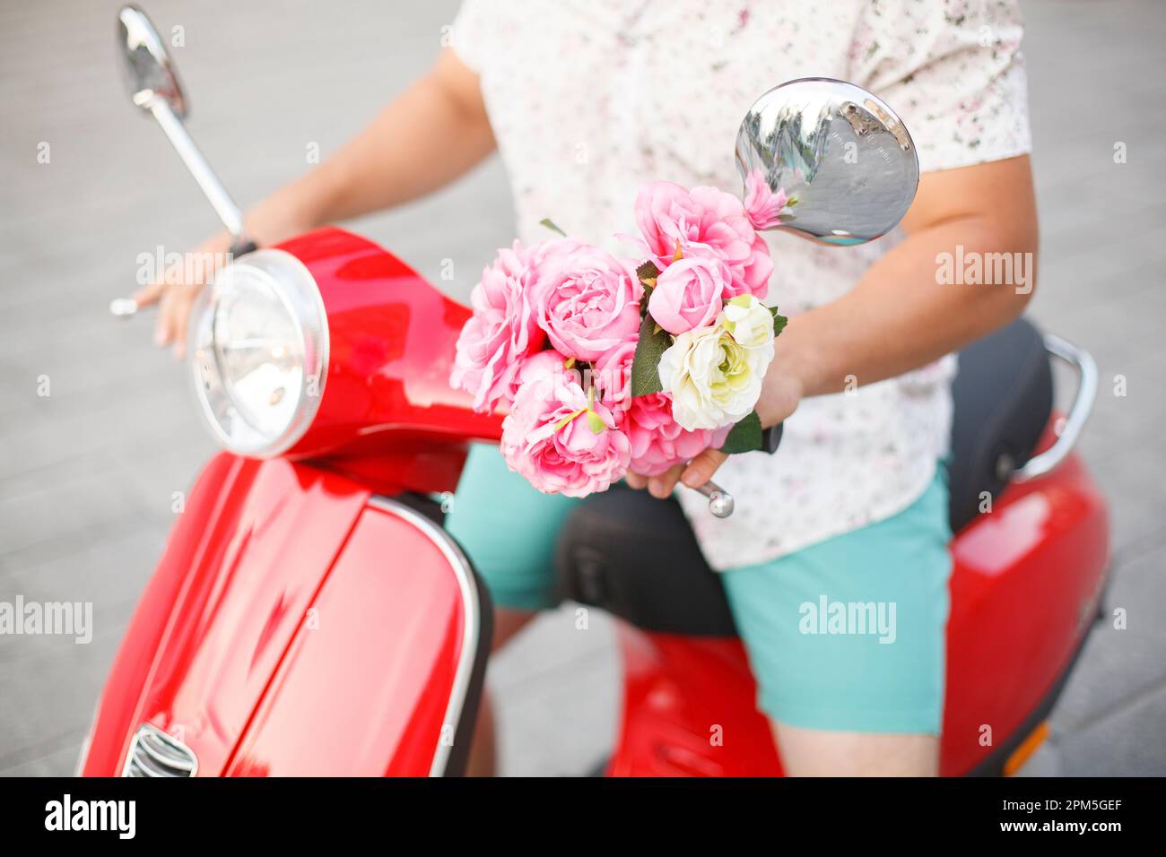 un homme va sur une date avec des fleurs sur un scooter de moteur Banque D'Images