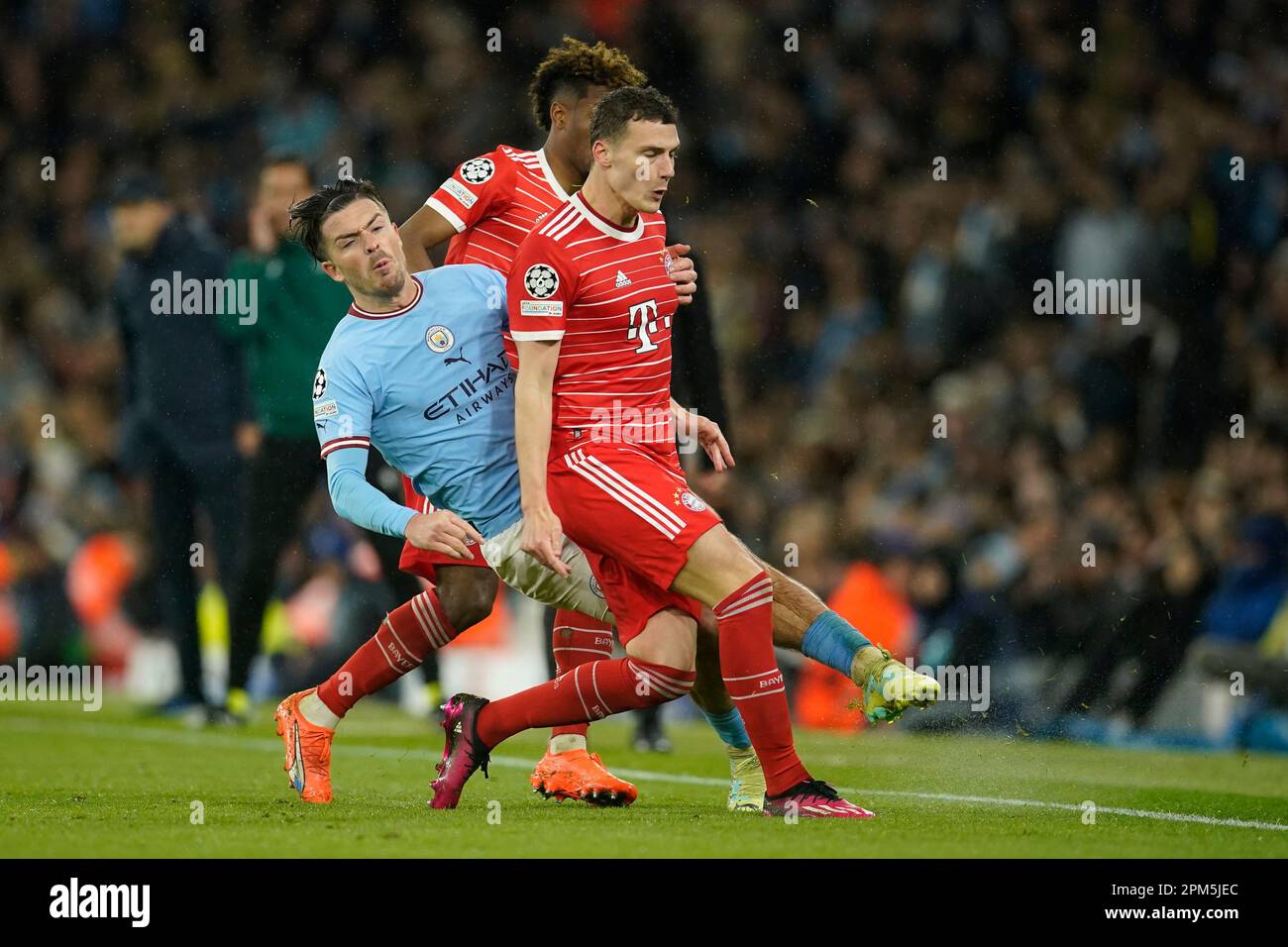 Bayern's Benjamin Pavard, right, and Kingsley Coman stop Manchester City's Jack Grealish during the Champions League quarterfinal, first leg, soccer match between Manchester City and Bayern Munich at the Etihad stadium in Manchester, England, Tuesday, April 11, 2023. (AP Photo/Dave Thompson) Banque D'Images