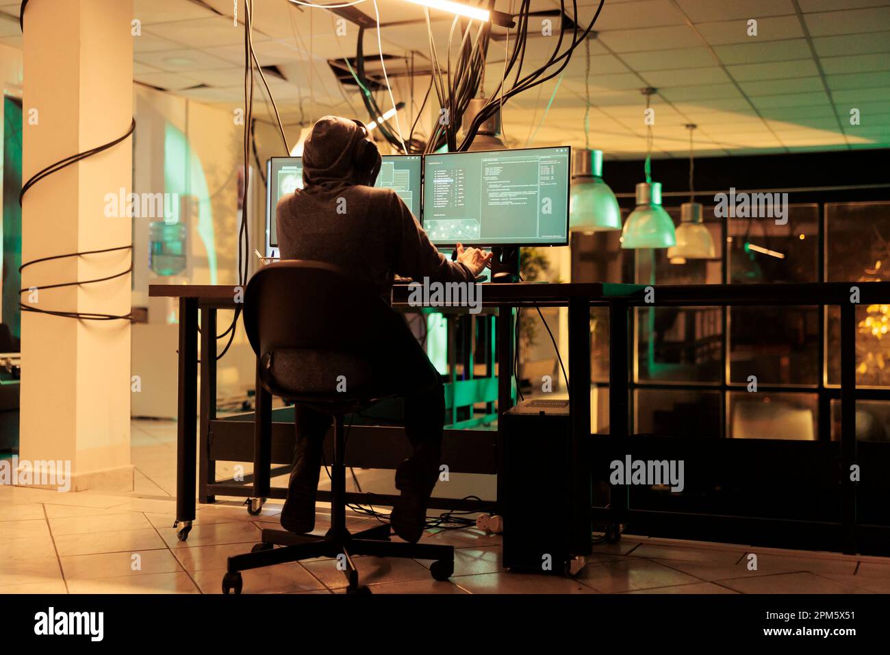 Espion anonyme utilisant plusieurs moniteurs pour craquer le cryptage, pirater la base de données personnelle et voler des mots de passe. Jeune regardant l'écran avec des codes pour pénétrer dans le réseau de banlieue la nuit. Banque D'Images