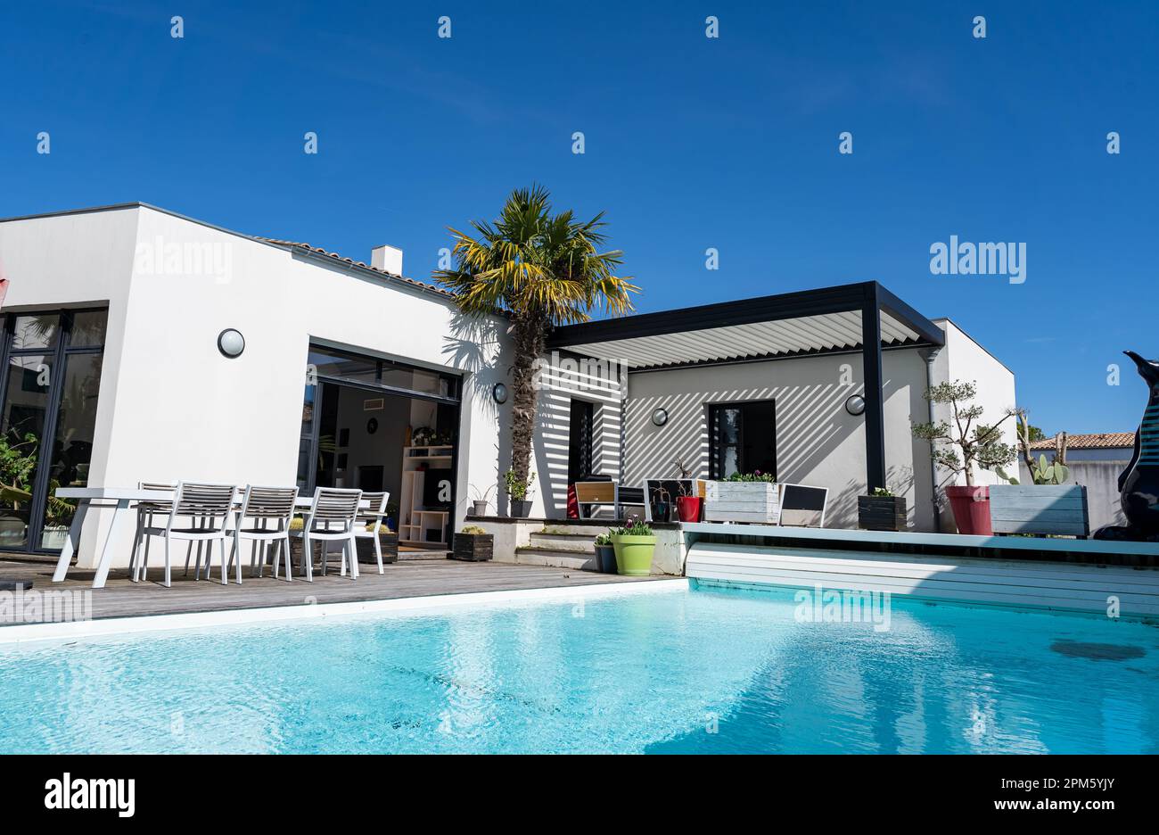 Patio extérieur tendance pergola structure d'ombre, auvent et toit de patio, salon de jardin, chaises, grill en métal entouré par l'aménagement paysager Banque D'Images