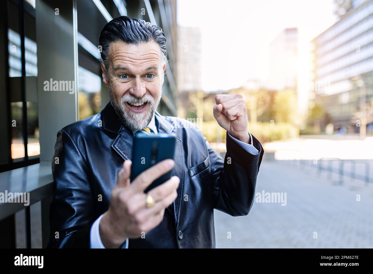 Portrait d'un homme d'affaires de direction célébrant les bonnes nouvelles au téléphone Banque D'Images