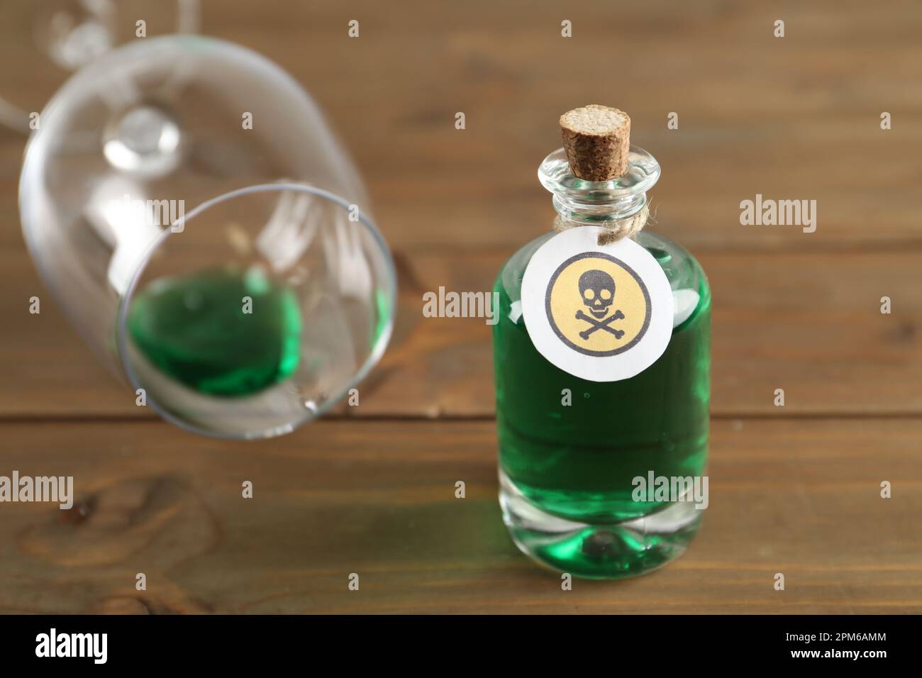 Bouteille de poison et verre partiellement vidé sur table en bois Banque D'Images