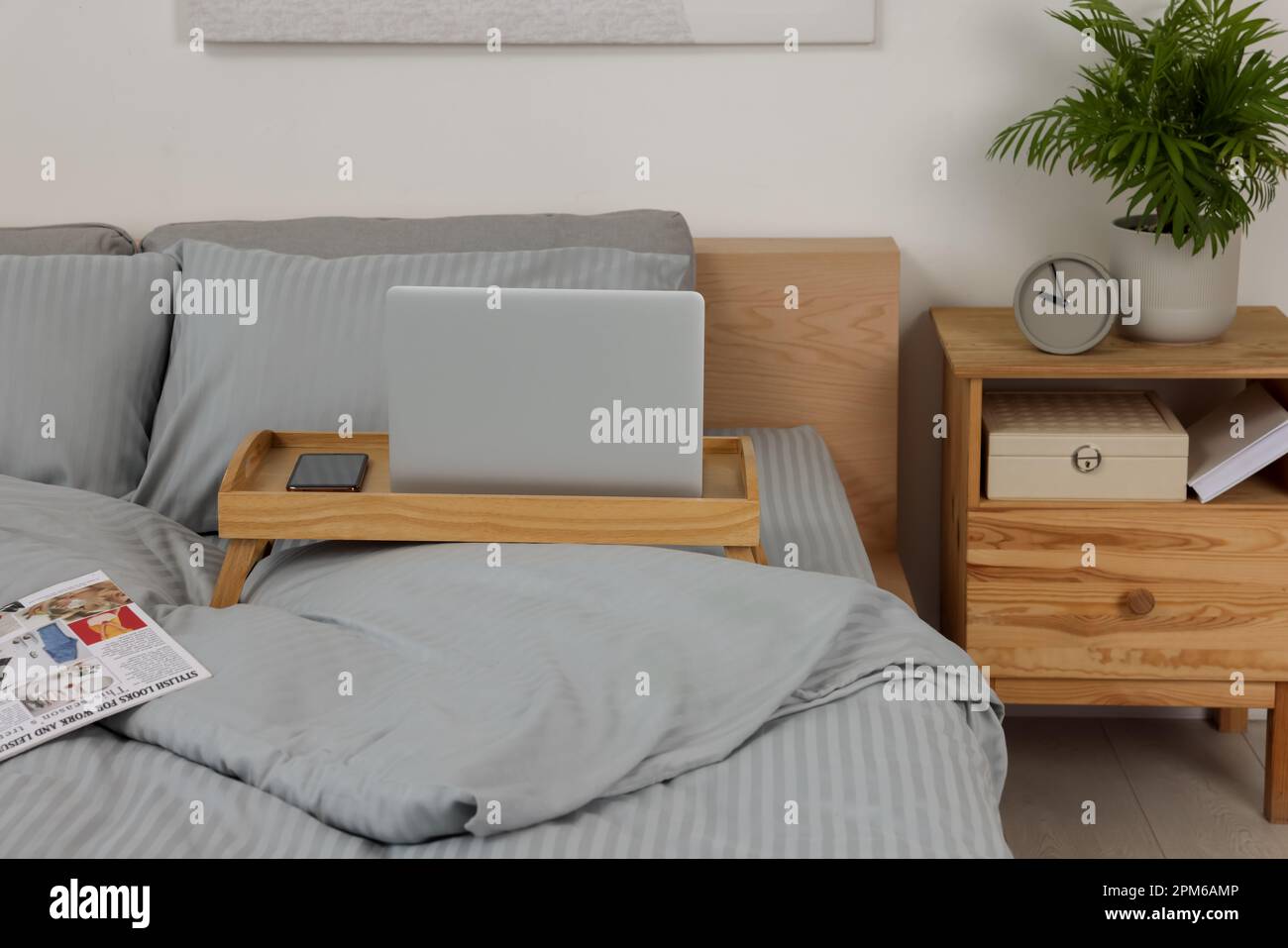Plateau table en bois avec ordinateur portable et smartphone sur le lit à l'intérieur Banque D'Images