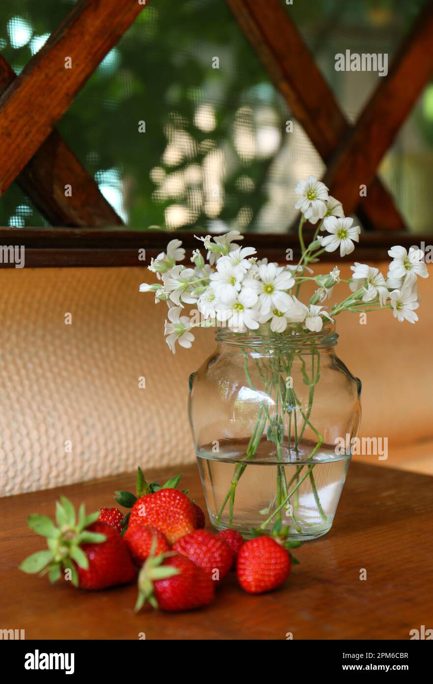 Fraises fraîches et bouquet de belles fleurs blanches sur table en bois Banque D'Images