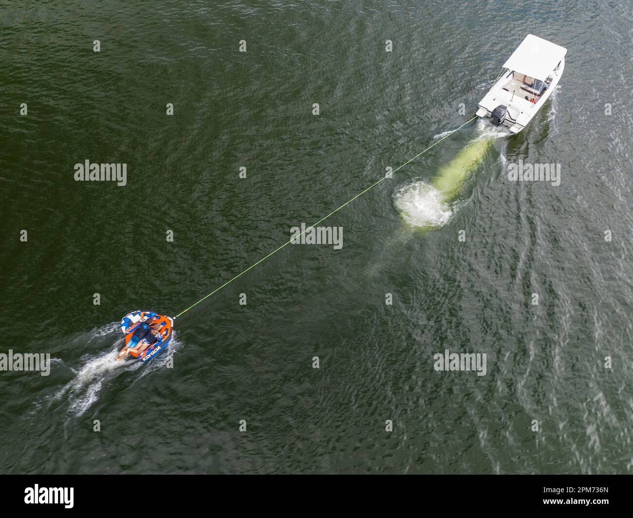 MacKay, Queensland, Australie - avril 2023 : drone aérienne d'un bateau à moteur remorquant des enfants sur des tubes à travers le barrage de Kinchant Banque D'Images