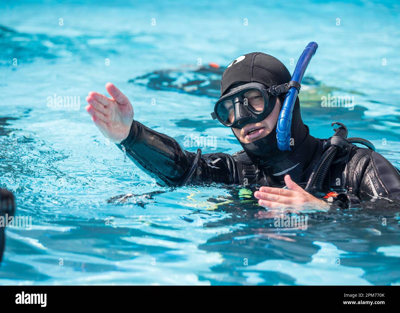 Instructeur de plongée sous-marine enseignant et expliquant aux élèves les compétences de récupération de régulateur dans la piscine Banque D'Images