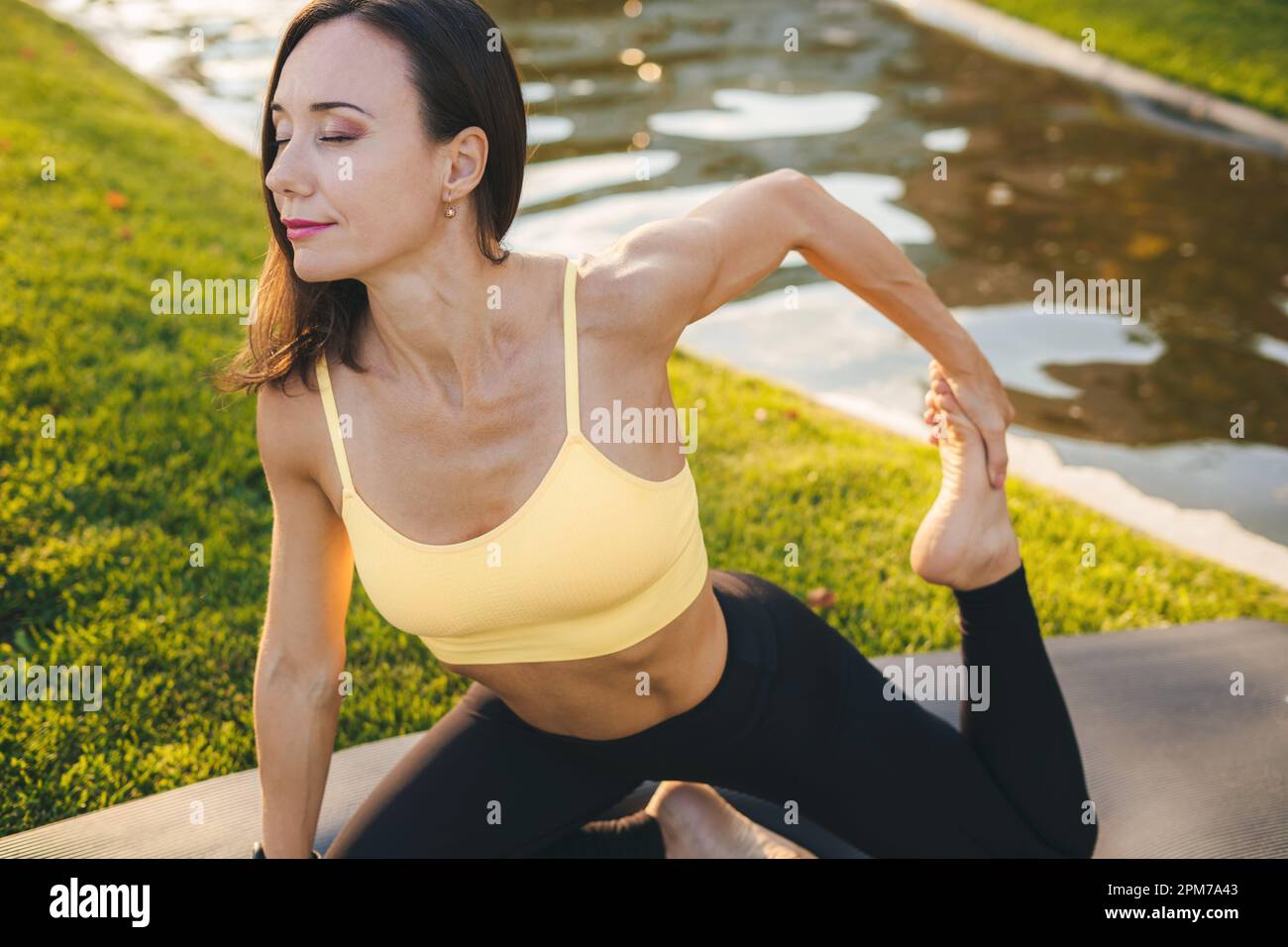 Femme mature faisant du sport et des exercices physiques à l'extérieur sur le tapis de yoga le matin. Les personnes s'exerçant. Femme assise à l'extérieur. Entraînement. Banque D'Images