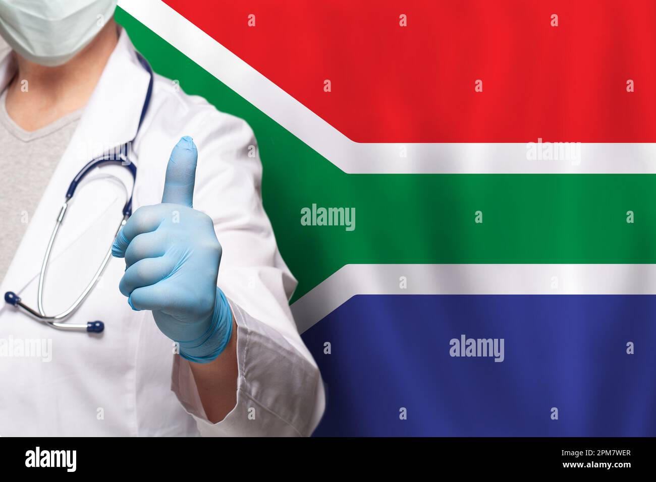Main du médecin sud-africain montrant le pouce vers le haut geste positif sur le drapeau de fond sud-africain Banque D'Images