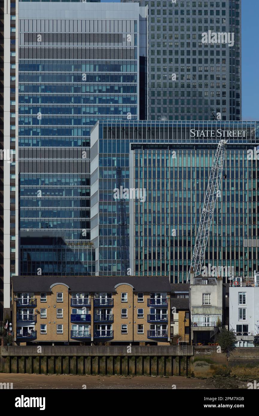 Les gratte-ciel de Canary Wharf, qui font partie du quartier central des affaires de Londres, dominent les anciens logements au bord de la Tamise au premier plan Banque D'Images