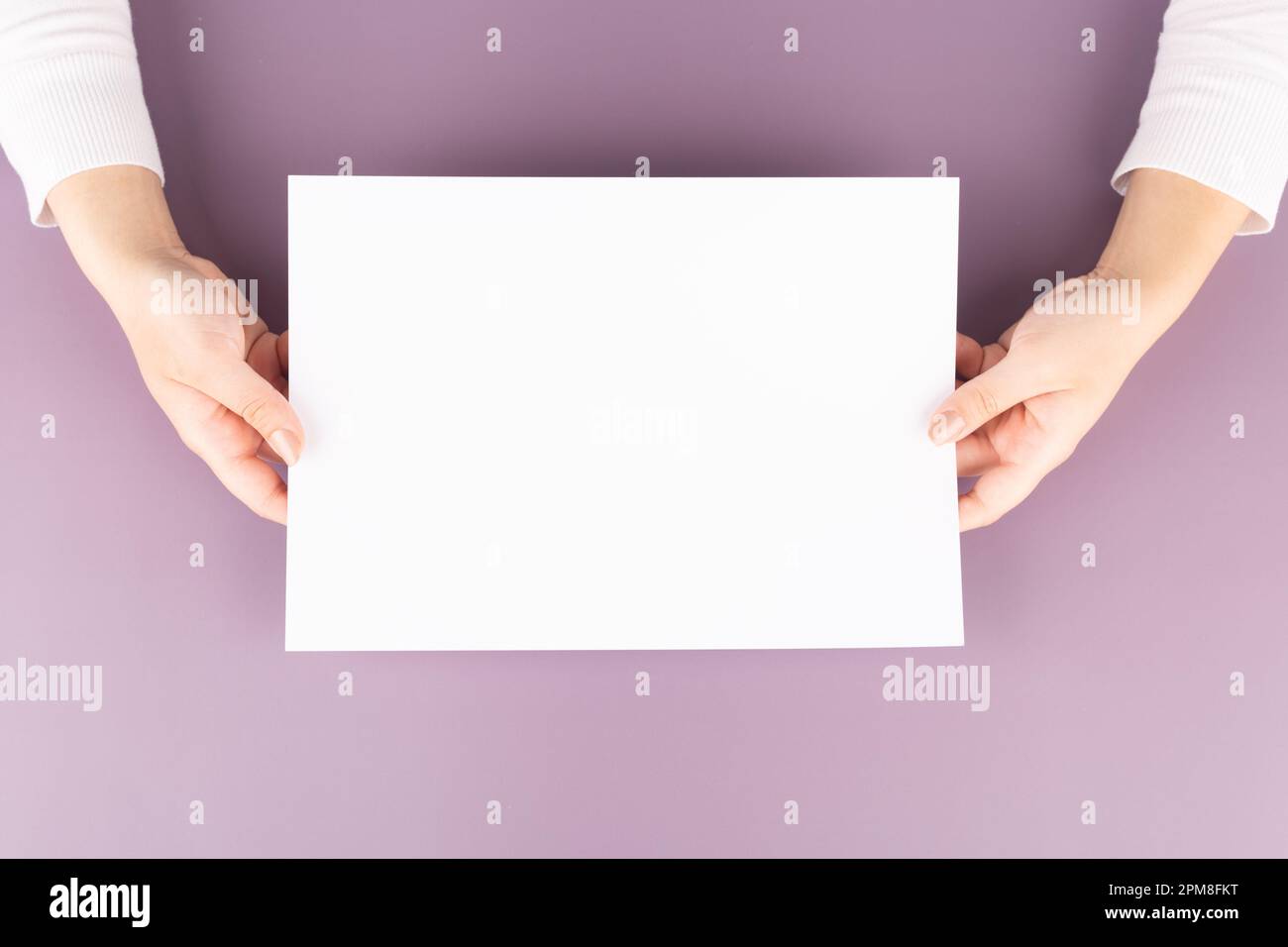 une femme tient une feuille de papier vierge dans ses mains. Espace publicitaire Banque D'Images