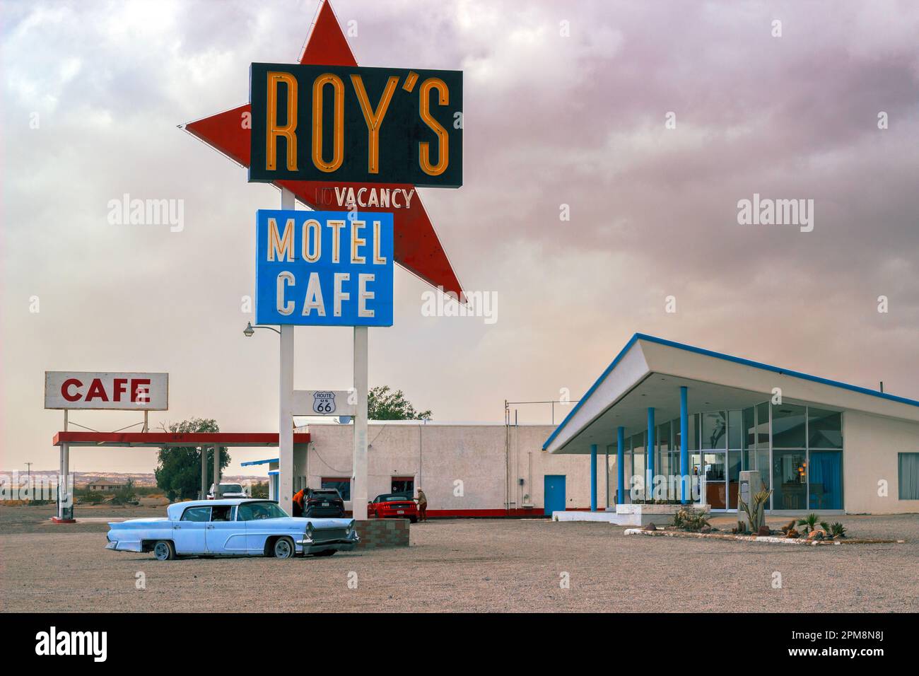 La photo montre un panneau et une voiture d'époque devant Roy's Motel, un célèbre motel abandonné situé dans la ville fantôme d'Amboy, Californie. Banque D'Images