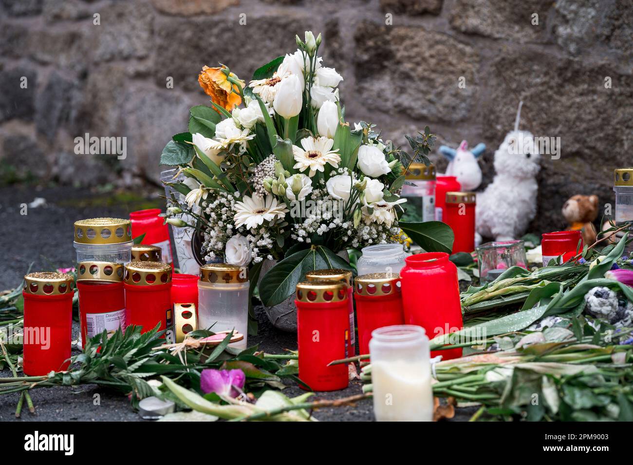 Wunsiedel, Allemagne. 12th avril 2023. Des fleurs, des jouets et des lumières de sépulture se trouvent sur le trottoir à l'angle de la rue menant au Centre des services à l'enfance et à la jeunesse, où une jeune fille de dix ans a été retrouvée morte. Credit: Daniel Vogl/dpa/Alay Live News Banque D'Images
