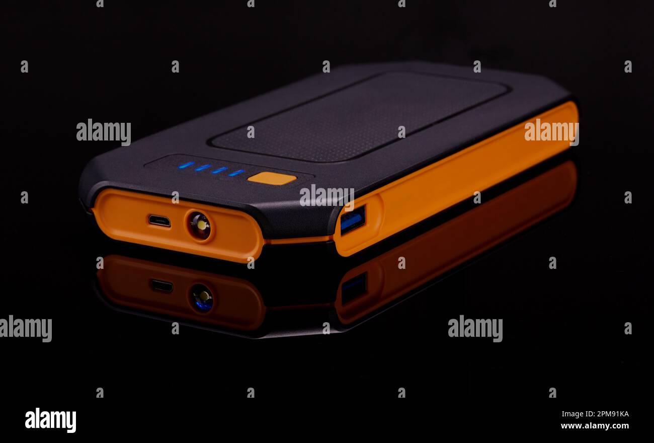 Chargeur de batterie isolé sur une surface réfléchissante noire froide. Banque D'Images