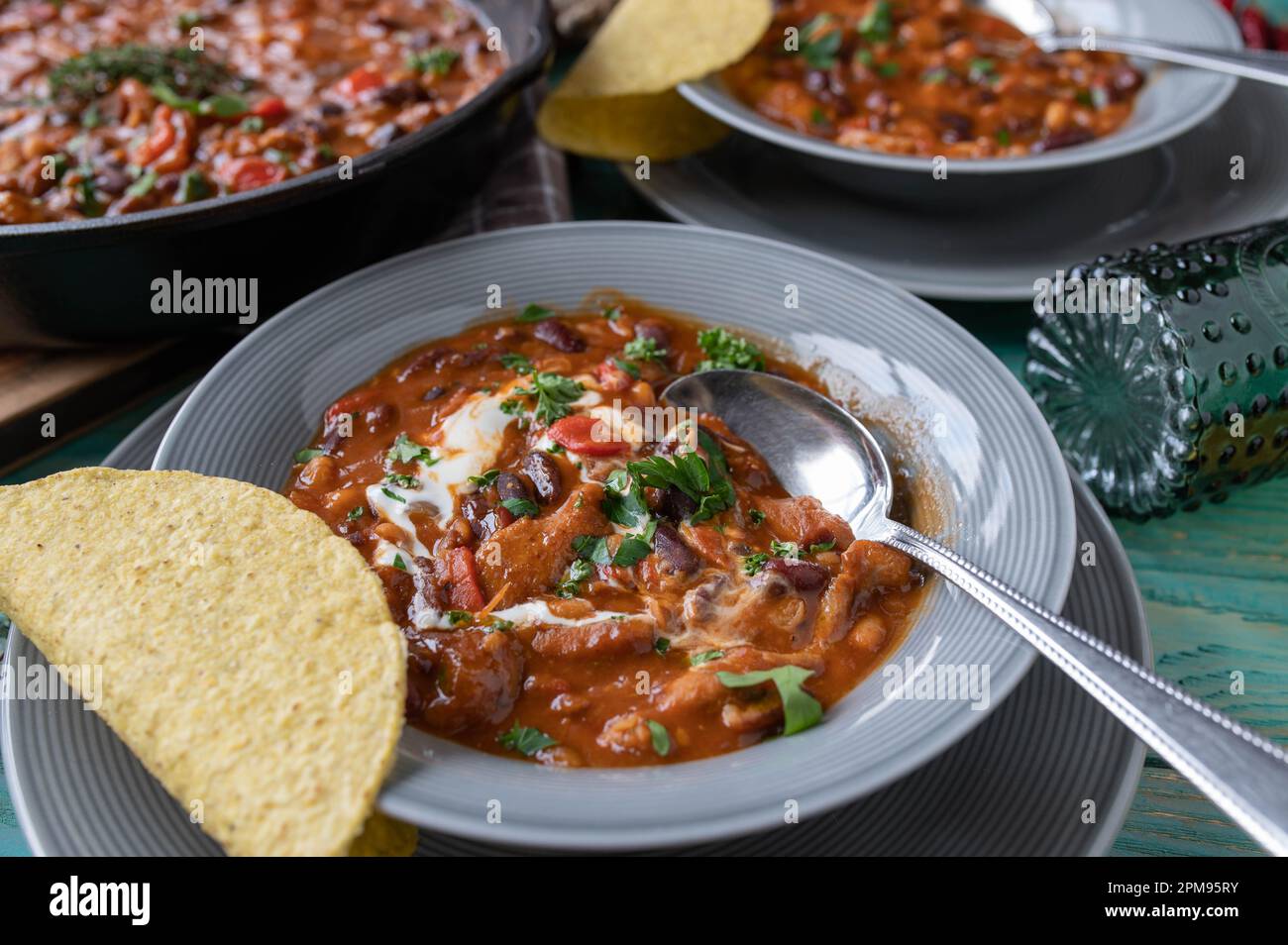 Ragoût de haricots Tex mex avec du poulet et de la crème aigre. Servi avec des tacos chauds Banque D'Images